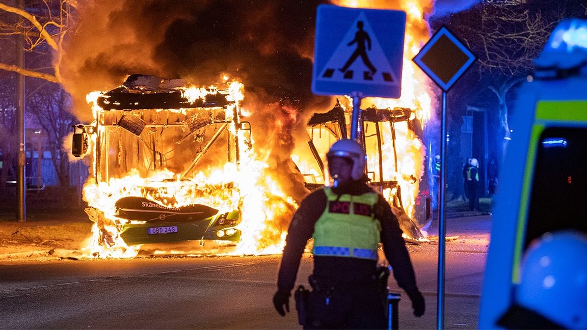 Kravallpolis på plats i Rosengård. I bakgrunden brinner en av Skånetrafikens statsbussar. Foto: Johan Nilsson/TT