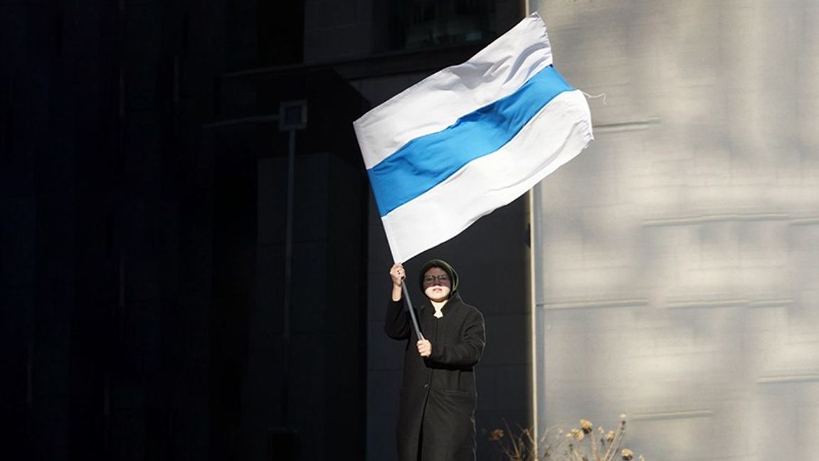 En kvinna håller upp den nya flaggan. Foto: Kira Popova (CC BY-SA 4.0)