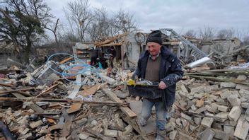 Ukrainsk man rensar bland rasorna i Lviv efter nattens attacker. Foto: Mykola Tys/AP/TT 