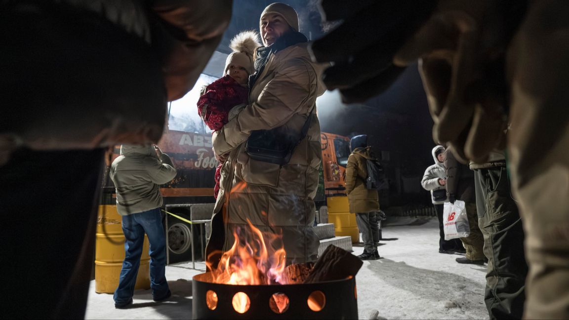 Kievbor värmer sig den 31 januari 2026 vid en eld i ett av bostadsområdena som drabbats värst och är utan fjärrvärme och el. Veteraner från den ukrainska armén tredje stormbrigad lagar samtidigt mat och bjuder de boende på ett varmt mål mat. Foto: AP Photo/Vladyslav Musiienko