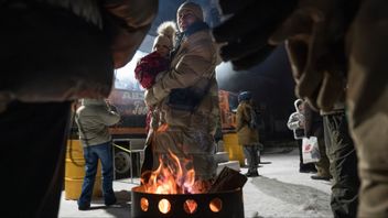 Kievbor värmer sig den 31 januari 2026 vid en eld i ett av bostadsområdena som drabbats värst och är utan fjärrvärme och el. Veteraner från den ukrainska armén tredje stormbrigad lagar samtidigt mat och bjuder de boende på ett varmt mål mat. Foto: AP Photo/Vladyslav Musiienko