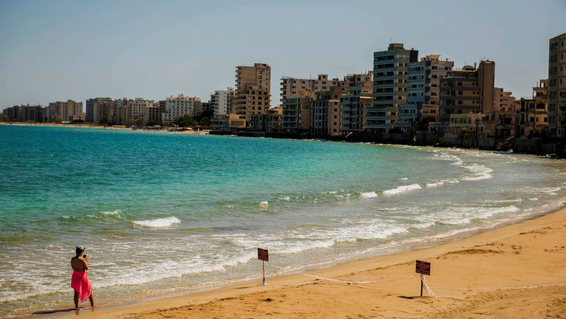 A bather checks her mobile phone as she strolls along an empty stretch of beach in the recently opened ghost suburb of Varosha on Saturday, Sept. 4, 2021. Photo: Nedim Enginsoy/AP/TT