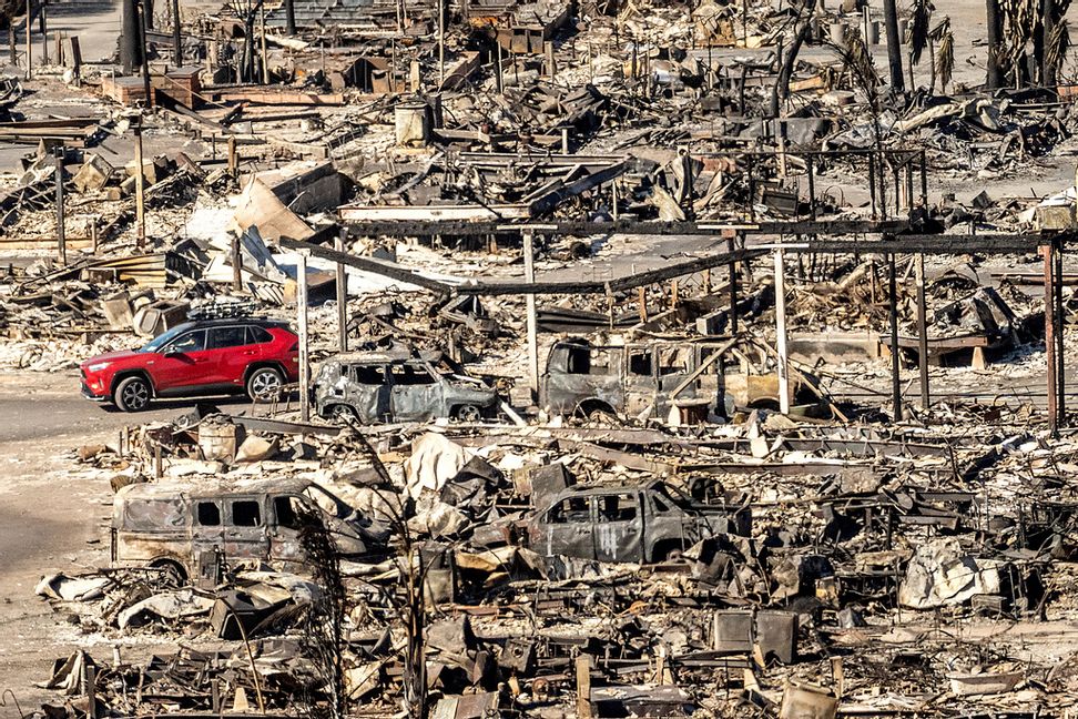 En bil passerar ett totalförstört kvarter i Pacific Palisades på söndagen. Noah Berger/AP/TT