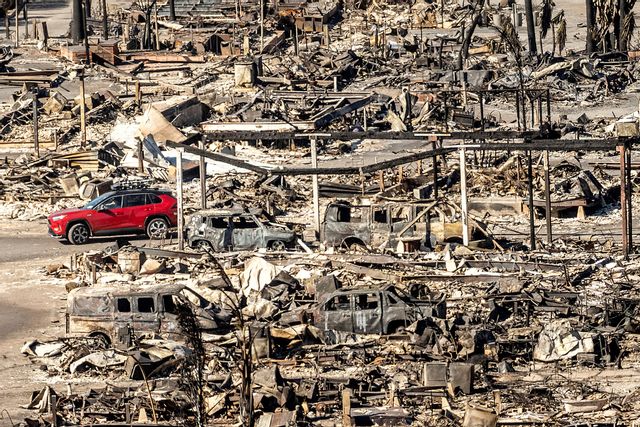 En bil passerar ett totalförstört kvarter i Pacific Palisades på söndagen. Noah Berger/AP/TT