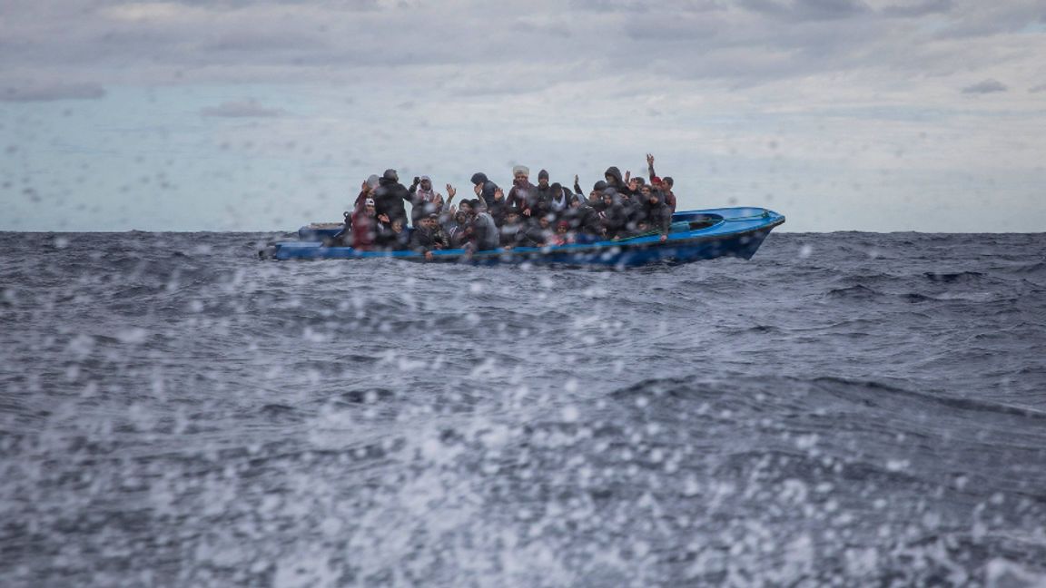 Män från Bangladesh och Marocko i en överfull träbåt på Medelhavet signalerar till räddningspersonal från den spanska organisationen Open Arms att de behöver hjälp. Arkivbild. Foto: AP/TT.