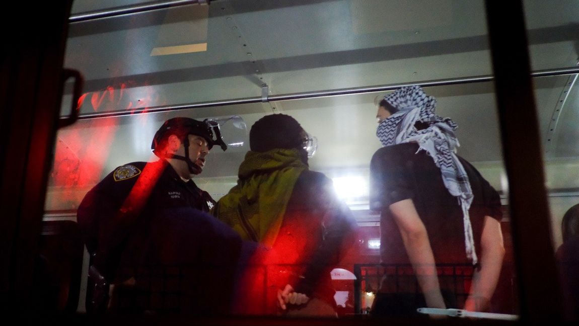 Frihetsberövade demonstranter vid campusområdet ombord på en polisbuss. Foto: JULIUS MOTAL/AP/TT