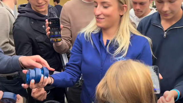 Ungsvenskarnas förbundsordförande Denice Westerberg delar ut dosor med SD:s partilogga utanför Tibble gymnasium i Täby. Foto: Facebook