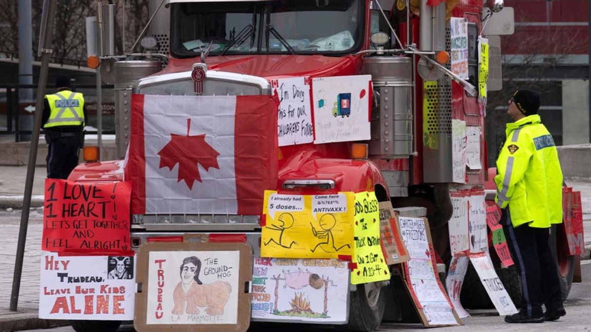 En polis i Kanadas huvudstad Ottawa försöker förmå protesterande lastbilschaufför att plocka ihop sina prylar och köra i väg. Foto: Adrian Wyld/AP/TT