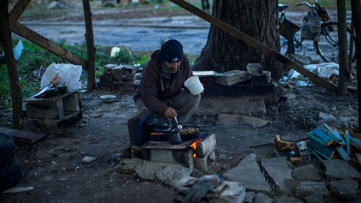 En man lagar mat utomhus i Kivsharivka i Ukraina. Foto: Francisco Seco/AP/TT 