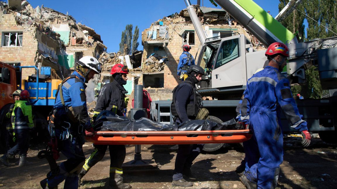 Ukrainska räddningstjänstmedarbetare bär bort ett dödsoffer framför ett bostadshus som skadades i den ryska attacken mot Kiev den 28 augusti 2025. Foto: AP Photo/Efrem Lukatsky