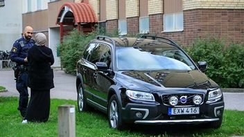 En polis talar med en kvinna utanför det hus i Gottsunda i Uppsala där en man hittades skjuten. Foto: Staffan Claesson/TT