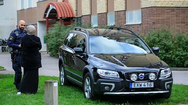 En polis talar med en kvinna utanför det hus i Gottsunda i Uppsala där en man hittades skjuten. Foto: Staffan Claesson/TT