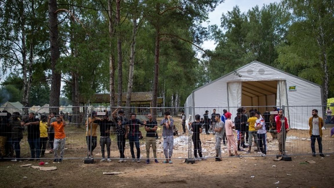 Migranter stående intill ett staket vid ett flyktingläger söder om Litauens huvudstad Vilnius. Foto: Mindaugas Kulbis/AP/TT