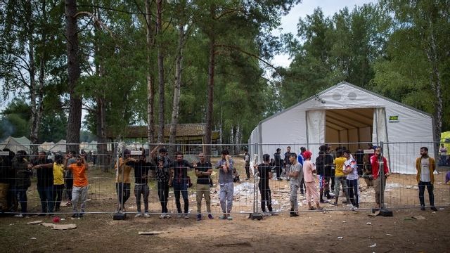 Migranter stående intill ett staket vid ett flyktingläger söder om Litauens huvudstad Vilnius. Foto: Mindaugas Kulbis/AP/TT