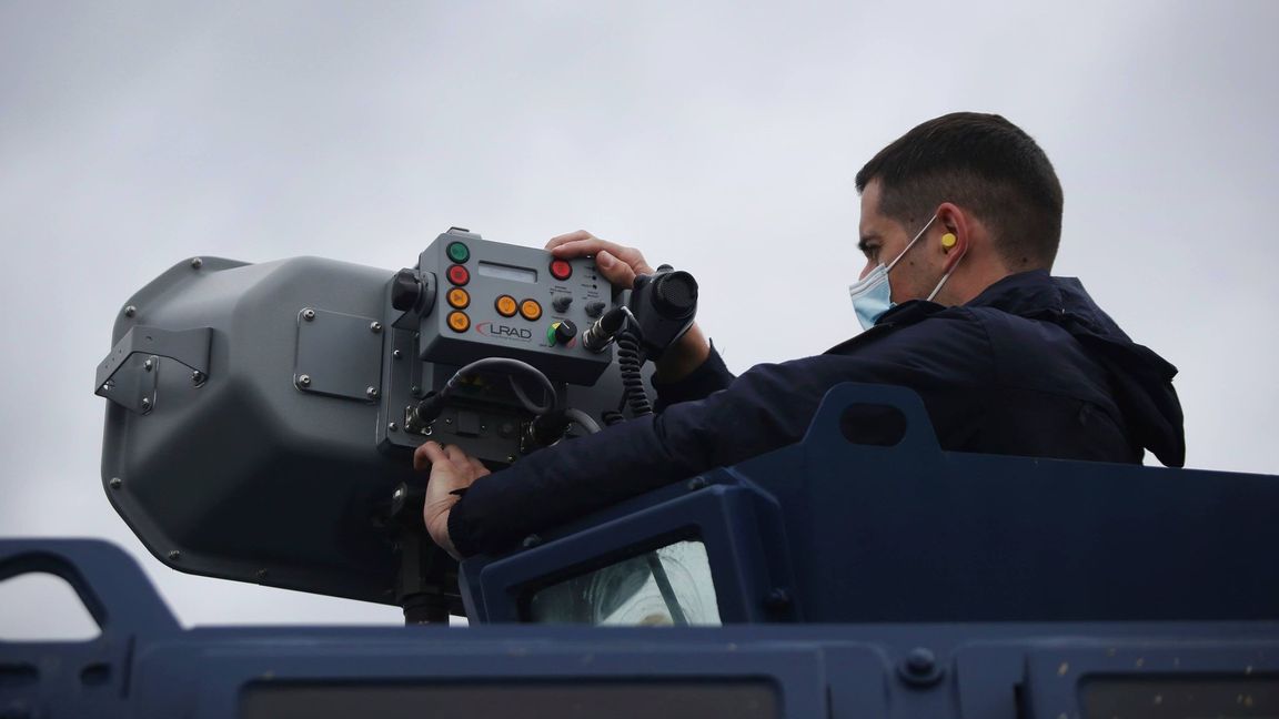 Polisen Dimitris Bistinas använder en så kallad Long Rande Acoustic Device (LRAD) som monterats på ett polisfordon längs den grekisk-turkiska gränsen nära den grekiska staden Feres. Foto: AP/TT.