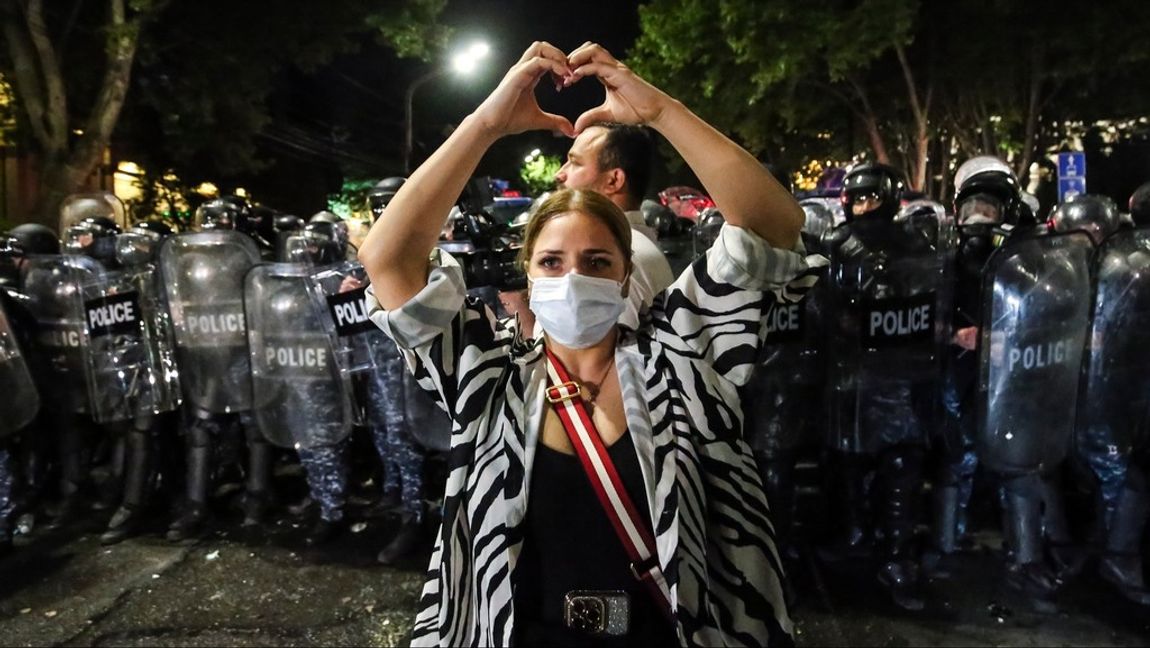 En kvinna gör ett hjärta med händerna framför kravallpolisen i Tbilisi natten till onsdagen. Foto: Zurab Tsertsvadze/AP/TT  