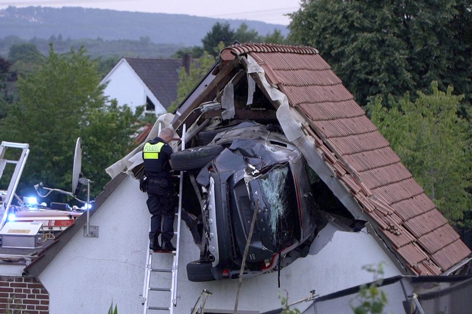 Polisen undersöker bilen som kraschat in i ett tak på en lada i nordvästra Tyskland på söndagen. Foto: Torben Kipp/AP/TT