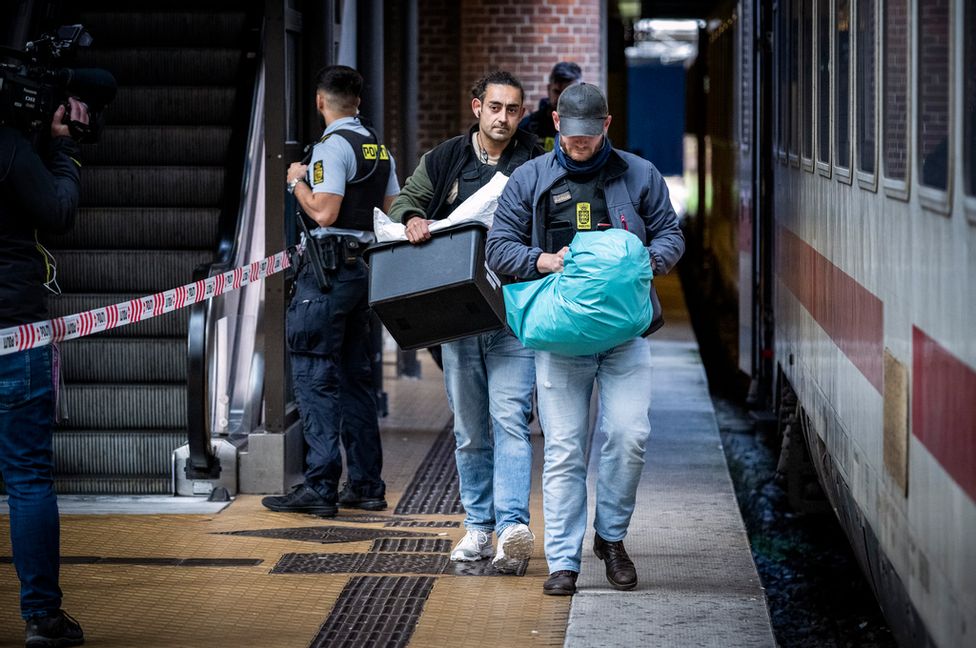 Dansk polis tar ett misstänkt farligt föremål som tillhör två svenskar som greps på ett tåg i Köpenhamn på onsdagen. Johan Nilsson/TT