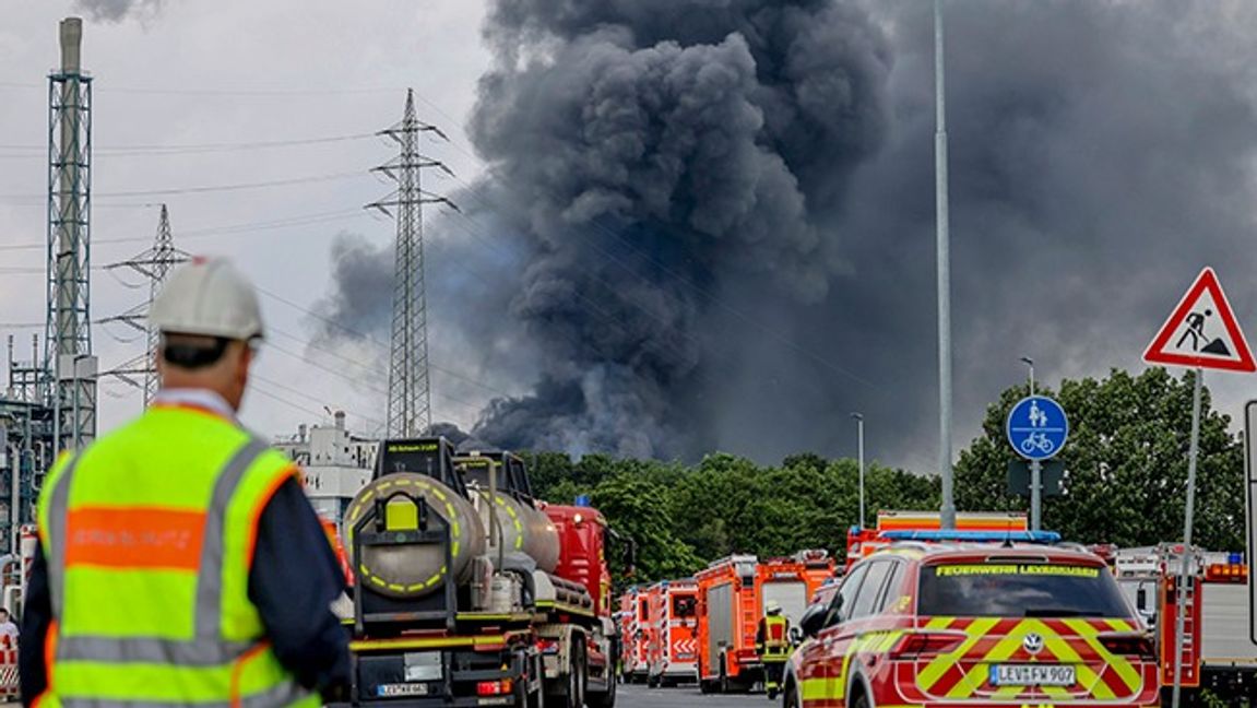 Räddningstjänst och polis håller sig på ett säkert avstånd från fabriken som sprutar ut giftig rök. Foto: 	Oliver Berg/AP/TT