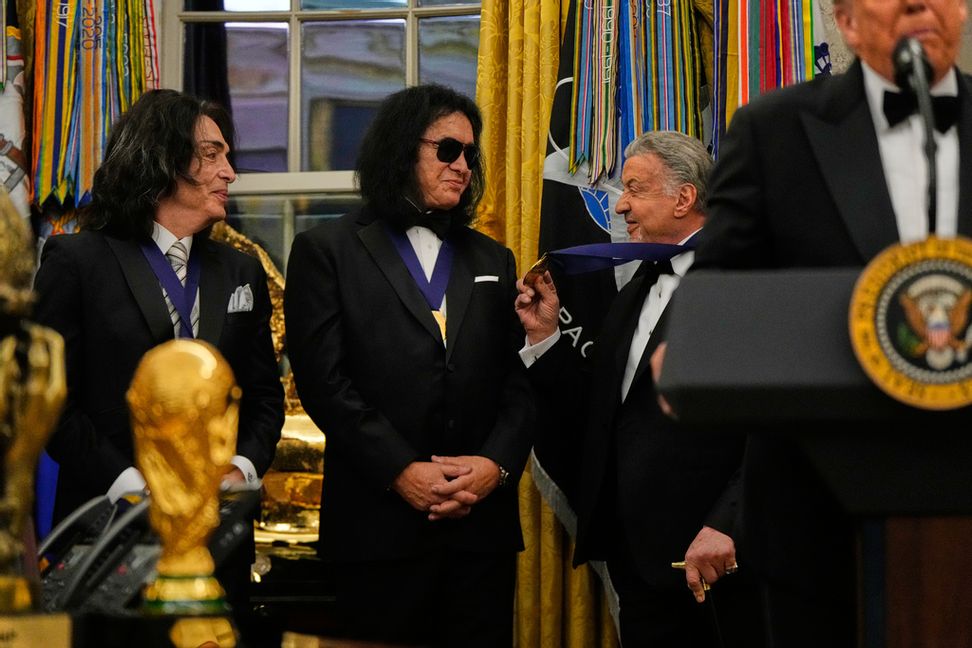 Sylvester Stallone visar upp sin medalj för Kiss-medlemmarna Paul Stanley och Gene Simmons under ceremonin, medan USA:s president Donald Trump talar. Foto: Julia Demaree Nikhinson/AP